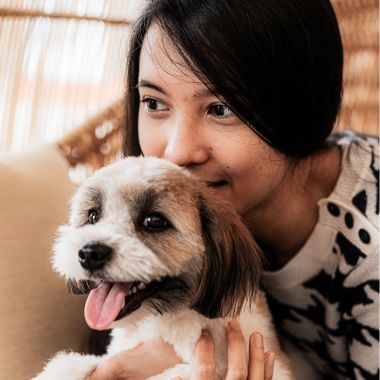 closeup of a woman holding her happy brown and white dog close